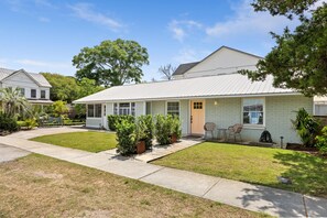 Uma casa térrea com varanda frontal, um pequeno gramado e um caminho que leva à entrada.