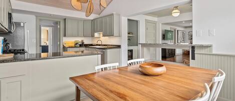 Una cocina moderna con una mesa de madera, sillas blancas y una lámpara colgante.