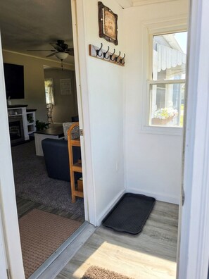 A doorway leading into a living room with a fireplace, a dining area, and a kitchen visible in the background.