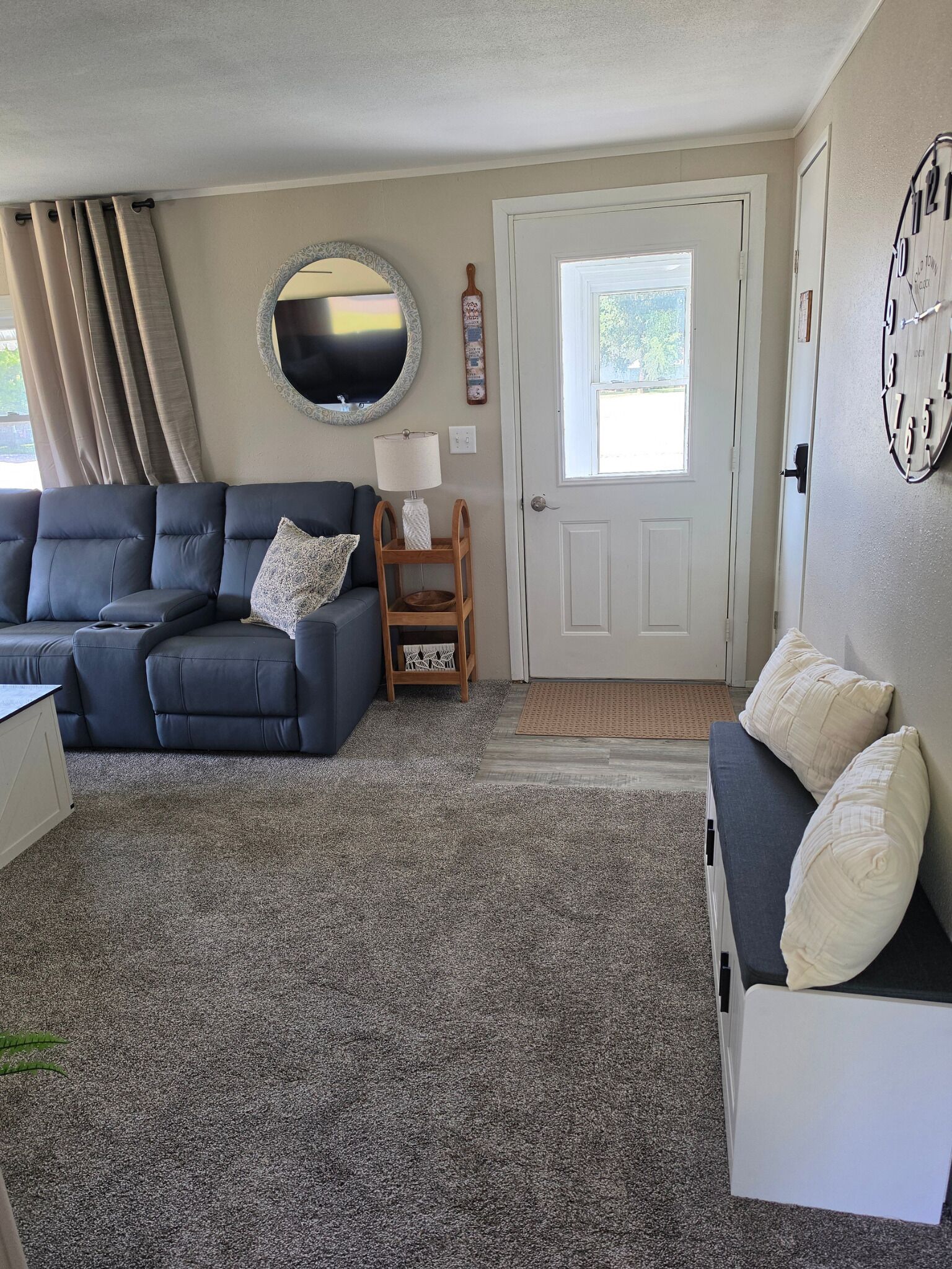 A living room with a sofa, a small wooden table, a mirror, and a door.