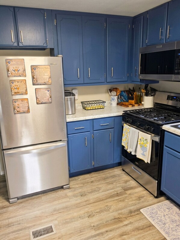 A kitchen with blue cabinets, stainless steel appliances, and a microwave.
