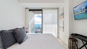 A hotel room with a bed, a small table, a painting, and a view of the ocean. - R401 Encantame Soleil – Stunning 3BR Condo with Beachside Views and Spacious Balcony (Puerto Peñasco)