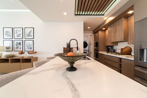A modern kitchen with a marble countertop, a sink with a black faucet, and wooden cabinets. - R401 Encantame Soleil – Stunning 3BR Condo with Beachside Views and Spacious Balcony (Puerto Peñasco)