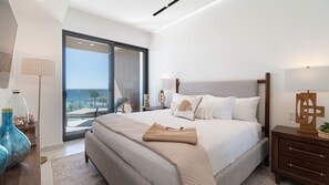 Un dormitorio moderno con una cama grande, vista al mar y un balcón.