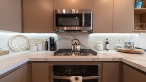 A modern kitchen with a stainless steel microwave, gas stove, and built-in oven. - R302: Stunning One Bedroom Beachfront Condo at Encantame Soleil (Puerto Peñasco)