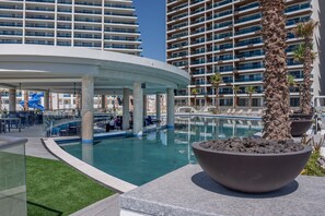 A modern hotel with a pool area, outdoor seating, and a palm tree. - One-bedroom condo at Encantame Soleil with king bed, ideal for a coastal escape. (Puerto Peñasco)