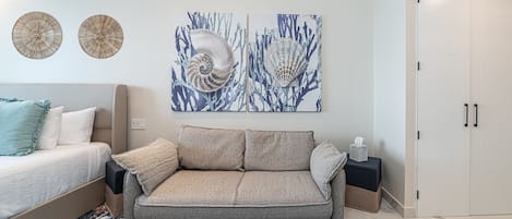 Ein neutrales Sofa mit strukturierter Stoffoberfläche, ein gemustertes Teppich und zwei dekorative Wandteller.