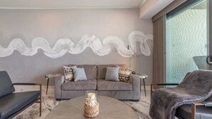 A modern living room with a grey sofa, two armchairs, a coffee table with a decorative item, and a large abstract painting on the wall. - R1102 Stylish Beachfront Escape with King Suite and Ocean Views (Puerto Peñasco)