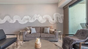 A modern living room with a grey sofa, two armchairs, a coffee table with a decorative item, and a large abstract painting on the wall. - R1102 Stylish Beachfront Escape with King Suite and Ocean Views (Puerto Peñasco)