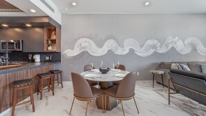 A modern kitchen with a built-in microwave and a dining area with a marble table and chairs. - R1102 Stylish Beachfront Escape with King Suite and Ocean Views (Puerto Peñasco)