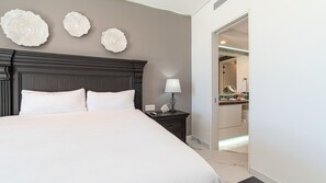 Ein Hotelzimmer mit einem großen Bett, einem dunklen Holz-Kopfschild, einem Nachttisch mit Lampe und einem durch eine offene Tür einsehbarer Badezimmer.