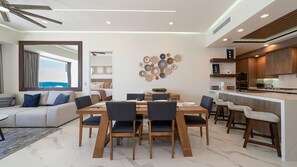 A modern living room with a dining area, a kitchen, and a view of the sea. - R504 Beachfront 3BR Condo with Ocean Views and Private Balcony at Encantame Soleil (Puerto Peñasco)