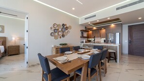 Una cucina moderna con elettrodomestici integrati, un'area pranzo con tavolo e sedie in legno, e un'opera d'arte decorativa a parete.