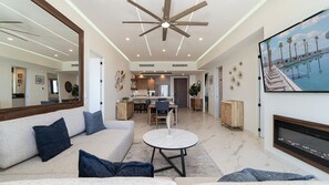 A spacious living room with a large sofa, a round coffee table, and a television mounted on the wall. - R504 Beachfront 3BR Condo with Ocean Views and Private Balcony at Encantame Soleil (Puerto Peñasco)