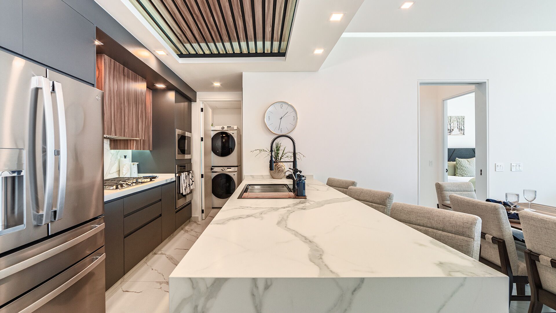 A modern kitchen with a marble island, stainless steel appliances, and a built-in oven.