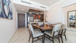Un espace repas moderne avec une table en bois, des chaises rembourrées et une cuisine en arrière-plan.