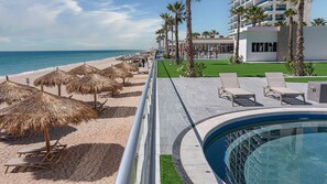 A resort pool area with a view of the beach, lounge chairs, and umbrellas. - R201 Luxury Oceanfront Retreat with Stunning Views and Spacious Modern Design (Puerto Peñasco)