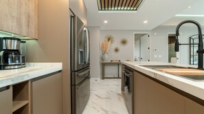 Uma cozinha moderna com eletrodomésticos de aço inoxidável, bancada de mármore e máquina de lavar louça embutida.