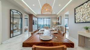 A spacious dining area with a large wooden table set for six, a modern pendant light, and a view of the outdoors. - R201 Luxury Oceanfront Retreat with Stunning Views and Spacious Modern Design (Puerto Peñasco)