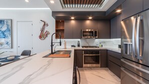 A modern kitchen with a built-in oven, a stainless steel refrigerator, and a microwave. - Stunning 2 bedroom High Floor Retreat at Encantame Soleil! (Puerto Peñasco)