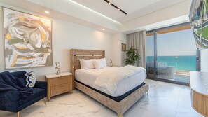A modern bedroom with a large bed, a nightstand, a chair, and a view of the ocean. - Stunning 2 bedroom High Floor Retreat at Encantame Soleil! (Puerto Peñasco)