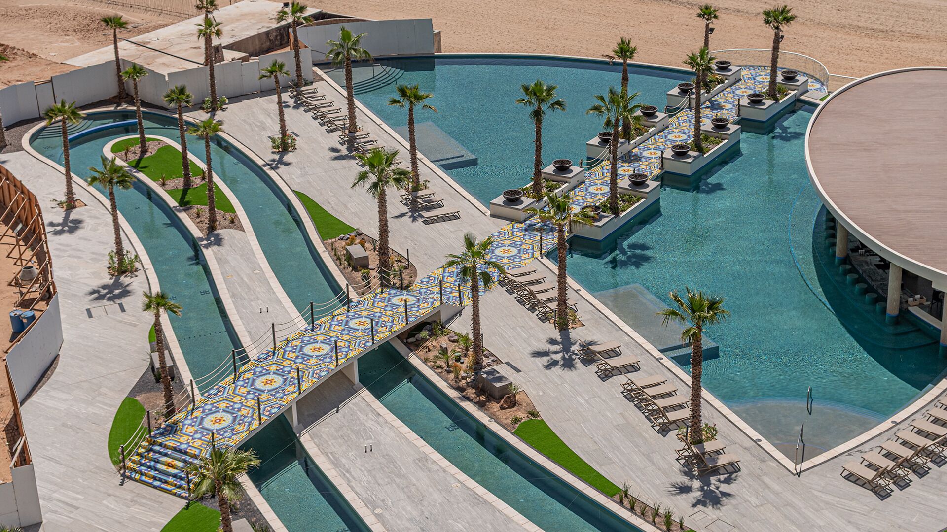 A resort pool with multiple lanes, palm trees, and lounge chairs.
