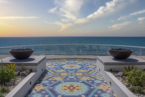 Ein mit Fliesen belegter Weg führt zu einem Pool mit Blick auf das Meer.