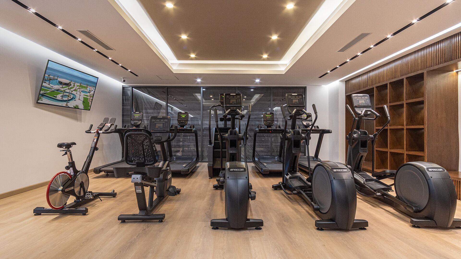 Un gimnasio con varias máquinas de ejercicio, una bicicleta y una pared de madera con un estante.