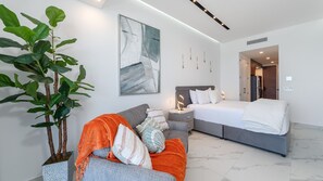 Ein modernes Schlafzimmer mit einem Bett, einem Schlafsofa, einem Nachttisch und einer großen Pflanze.