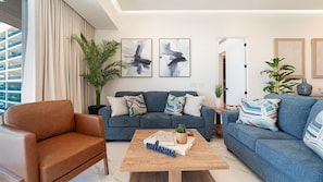 A modern living room with a sofa set, a coffee table, and a potted plant. - R1701 Beachfront 3BR Condo with Dual Balcony Access & Spacious Open Living (Puerto Peñasco)