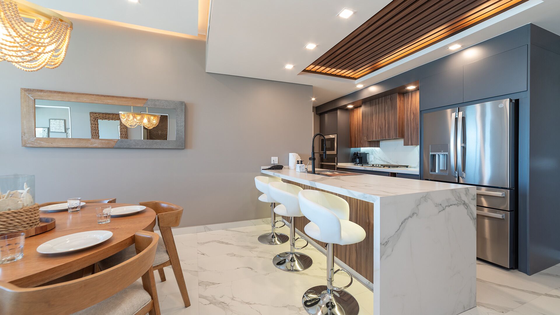 A modern kitchen with a central island, bar stools, and stainless steel appliances.
