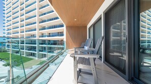 Varanda com mesa e cadeiras, vista para um edifício moderno com várias varandas.