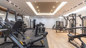 Ein Fitnessstudio mit verschiedenen Trainingsgeräten, darunter Kraftgeräte und Kurzhanteln.