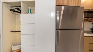 Eine Küche mit einem Edelstahl-Kühlschrank, Holzschränken und einer Kleiderstange.