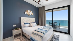 A bedroom with a large bed, a nightstand, a decorative wall piece, and a view of the sea through a sliding door. - R1605 2BR, 2BA condo on the 14th floor at Encantame Soleil in Puerto Peñasco. (Puerto Peñasco)