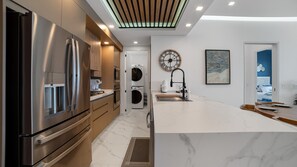 A modern kitchen with stainless steel appliances, a marble countertop, and a built-in washing machine. - R1605 2BR, 2BA condo on the 14th floor at Encantame Soleil in Puerto Peñasco. (Puerto Peñasco)