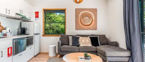 A modern living space with a kitchen, a sofa, a coffee table, and artwork on the walls.