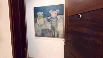 Un pasillo con puerta de madera, suelo de mármol y un cuadro en la pared.