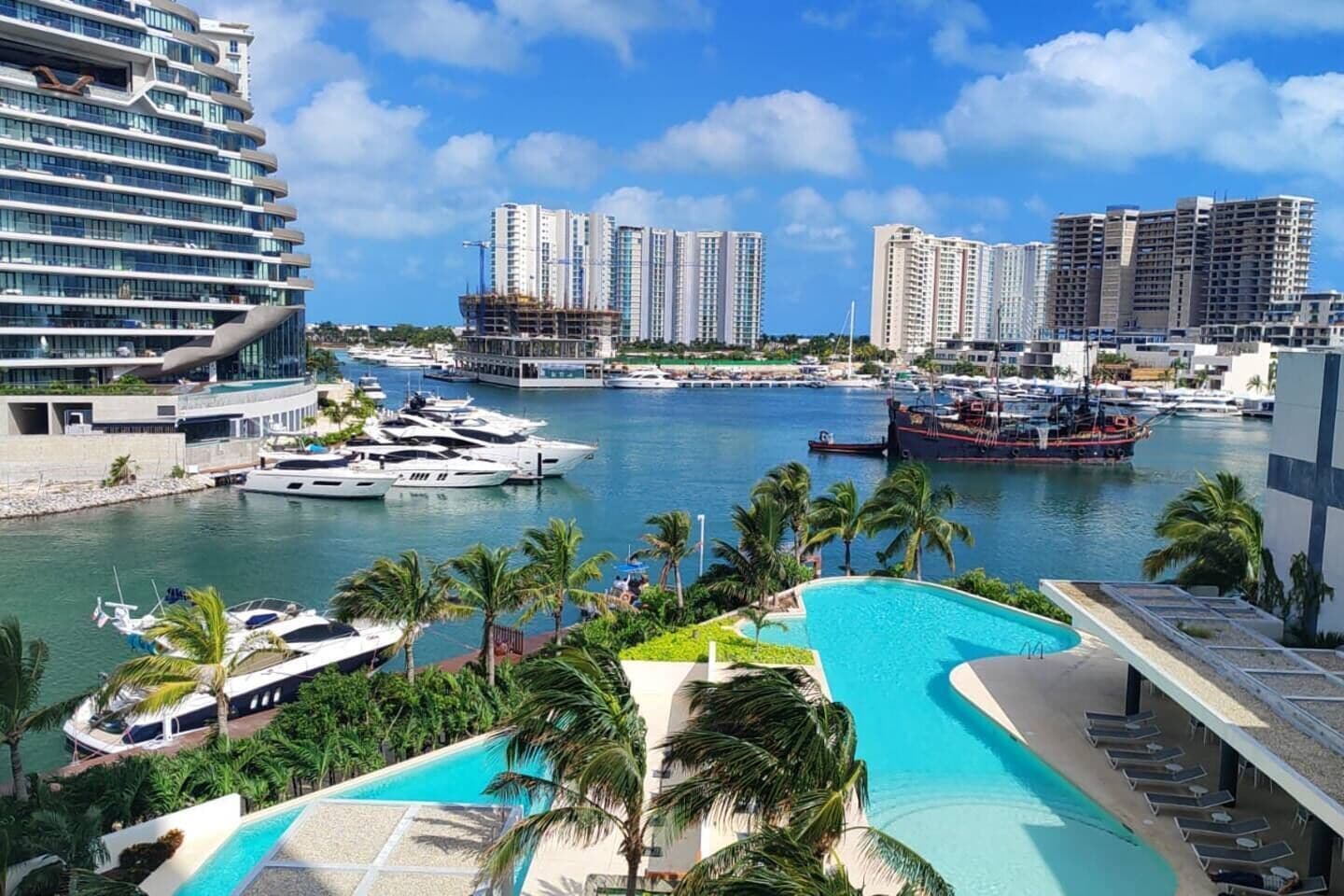 Eine Marina mit Yachten, einem Schwimmbad und Hochhäusern im Hintergrund.
