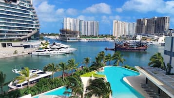 Eine Marina mit Yachten, einem Schwimmbad und Hochhäusern im Hintergrund.