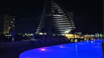 Vista nocturna de un edificio moderno con zona de piscina.
