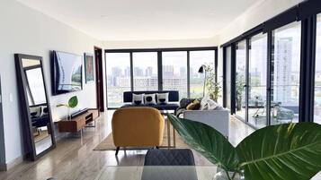 Un salon moderne avec une grande fenêtre, un canapé, une table basse et un téléviseur.