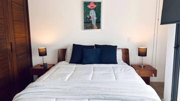 Une chambre d’hôtel avec un grand lit, deux tables de chevet avec des lampes, une armoire en bois et un tableau au mur.