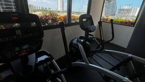 A gym with exercise equipment and a view of city buildings. - TOP/4BR/Million Dlls Sea Views/4 Balcony/Padel/Gym (Cancún)