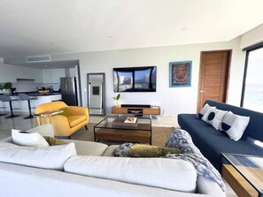 A modern living room with a sofa, armchair, coffee table, and a television. - Vista al Caribe · 4 balcones · Plaza Marina · TOP (Cancún)