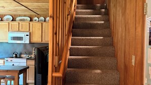 A staircase with a wooden railing leading to a second floor. - Spacious, waterfront privacy in Lake Leelanau , the heart of Leelanau County (Lake Leelanau)