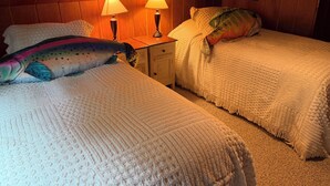 Een gezellige kamer met twee bedden, een houten plafond en twee bedlampjes.