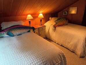 Una camera accogliente con due letti, un soffitto in legno e due lampade da comodino.