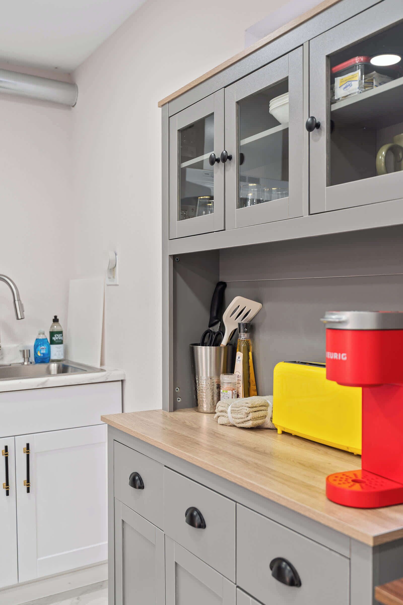 A kitchen with a sink, cabinets, and a coffee machine.