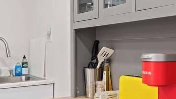 A kitchen with a sink, cabinets, and a coffee machine.